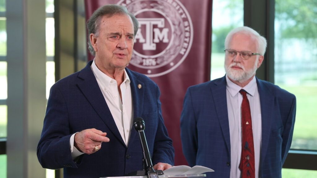 John Sharp speaks behind a podium at an event.