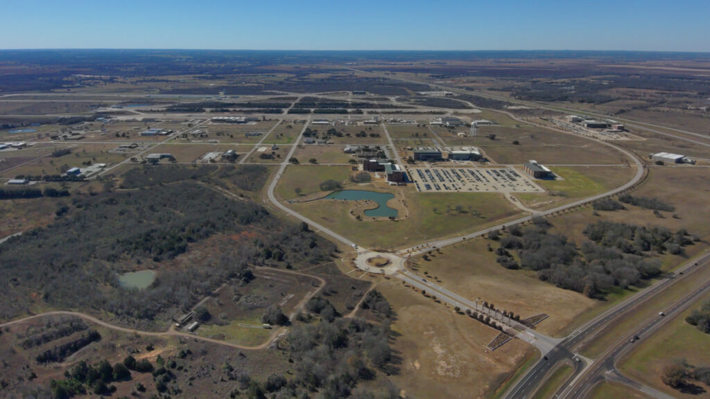 Aerial view of the Texas A&M–RELLIS Campus in Bryan, Texas, showing academic and research facilities, roadways, parking areas, ponds and open land slated for future development.